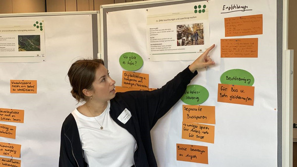 Eine Frau zeigt auf eine Pinnwand.