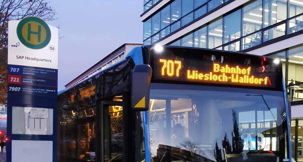 Ein Bus hält an einer Haltestelle vor einem Bürogebäude der Firma SAP.