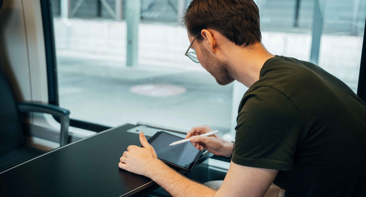 Mann arbeitet am Tablet in einem Zug.