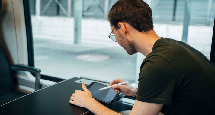 Mann arbeitet am Tablet in einem Zug.