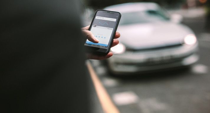 Mann, der die Abholung mit einem Auto auf seinem Telefon organisiert.