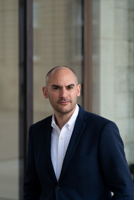 Porträtbilder Minister Dr. Danyal Bayaz orträt von Finanzminister Danyal Bayaz vor dem Kunstgebäude am Schlossplatz in Stuttgart, mit Glasfassade und Steinstruktur im Hintergrund.