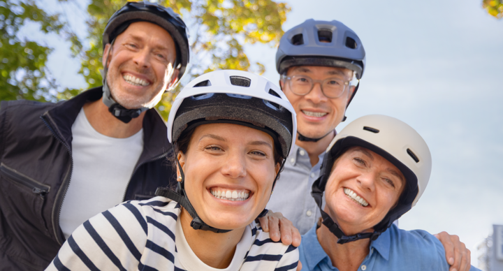 Vier Menschen mit Fahrradhelm lächeln in die Kamera