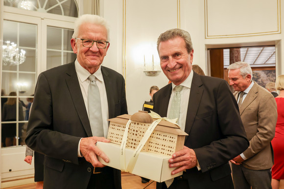 Empfang 70. Geburtstag von Günther H. Oettinger Ministerpräsident Winfried Kretschmann (links) überreicht dem ehemaligen Ministerpräsidenten Günther Oettinger (rechts) bei einem Empfang anlässlich dessen 70. Geburtstages ein Bienenhotel in Form der Villa Reitzenstein.