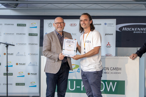 Elektromobilität e4 TESTIVAL auf dem Hockenheimring Verkehrsminister Winfried Hermann MdL bei der Übergabe der Urkunde an Manuel Messmer von SOL Motors, einem der zwölf Finalisten des Start-up Awards 2019 im Rahmen des e4 TESTIVAL (Bilderquelle: Kira Chaparro_© emodrom)