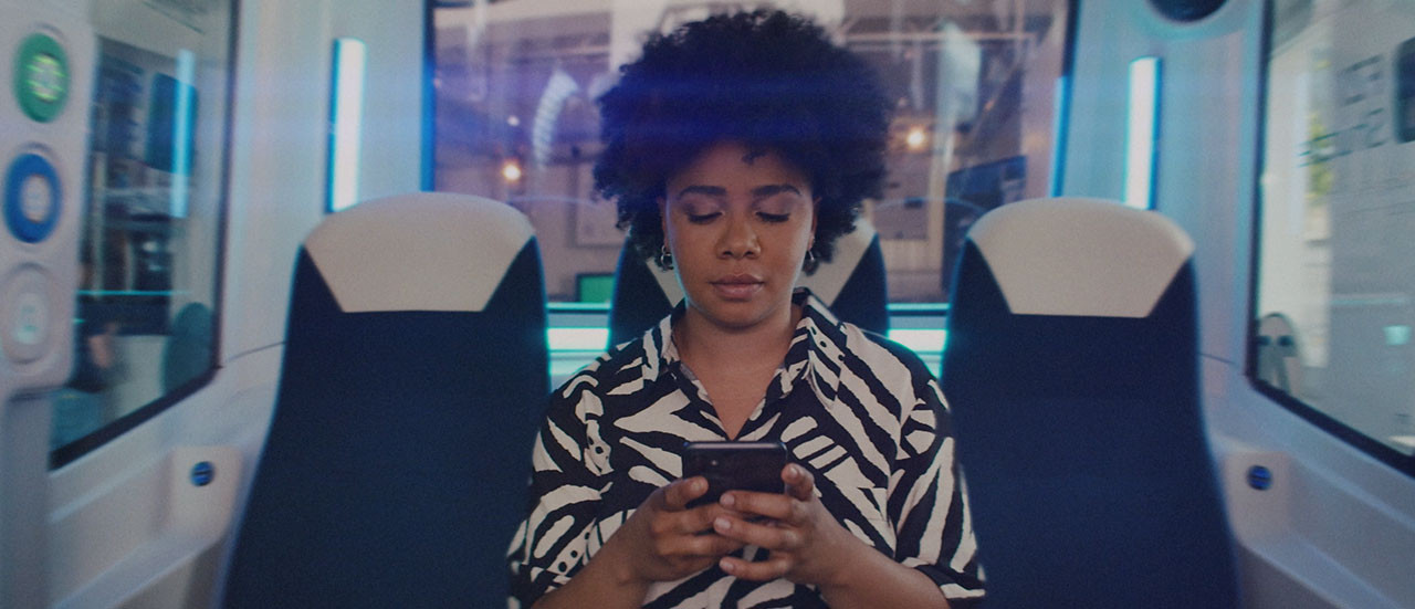 Eine Frau sitz in einem Kleinbus und schaut abwesend auf ihr Handy.