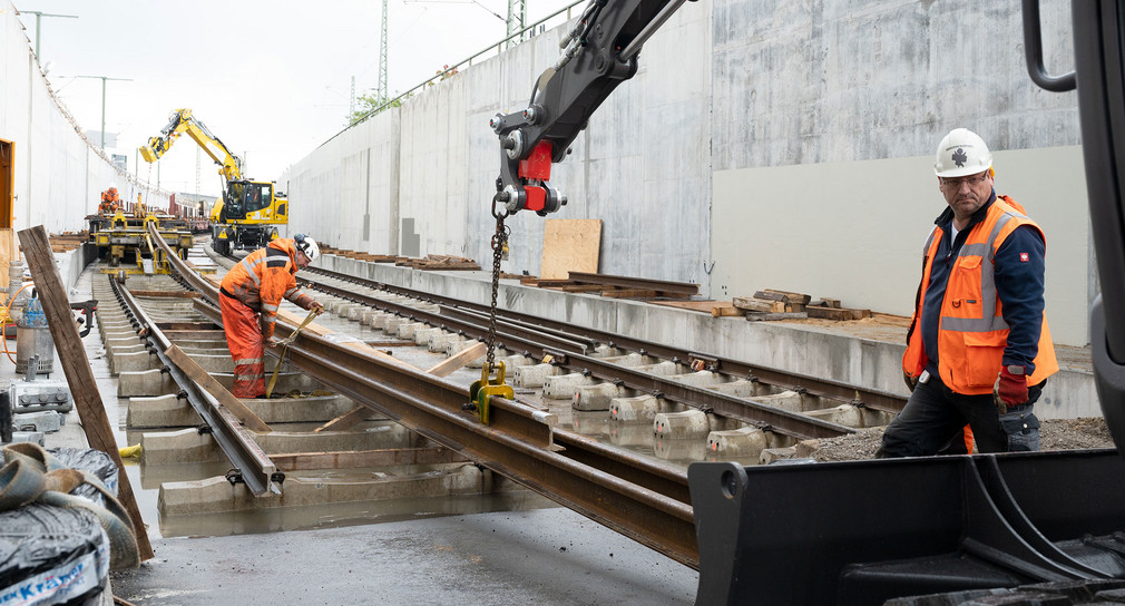 Bahngleise werden von zwei Arbeitern auf einer Baustelle verlegt.