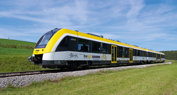 Netz 12 Ulmer Stern Zugtyp Alstom Coradia Lint 54 auf einem Gleis in einer grünen Landschaft.