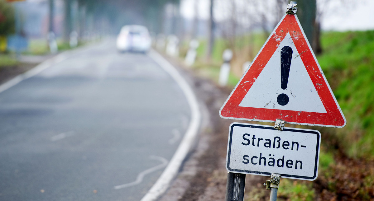 Schild warnt vor Straßenschäden.