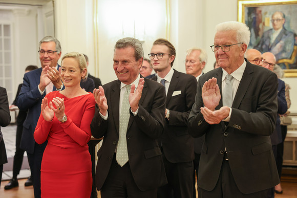 Empfang 70. Geburtstag von Günther H. Oettinger von links nach rechts (vorne): Friederike Beyer, der ehemalige Ministerpräsident Günther H. Oettinger und Ministerpräsident Winfried Kretschmann stehen im Runden Sall der Villa Reitzenstein und applaudieren.