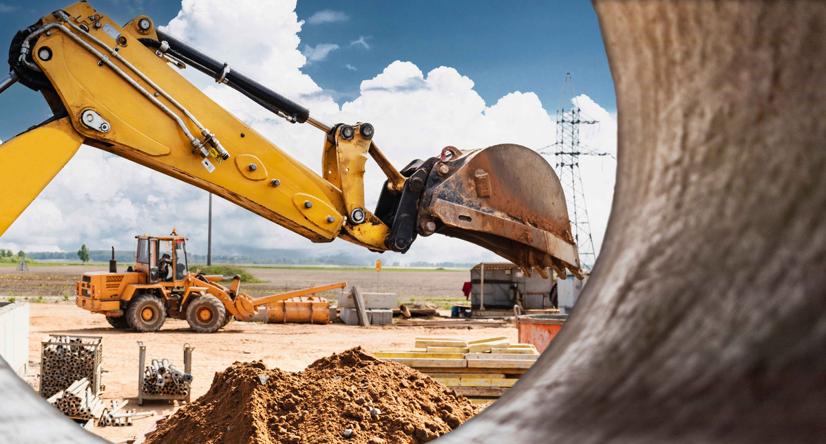 Bagger gräbt Pfähle. Erdarbeiten für den Bau des Fundaments. Baumaschinen für die Pfahlgründung. Vorarbeiten für den Grillrost. Blick von einem großen Betonrohr.