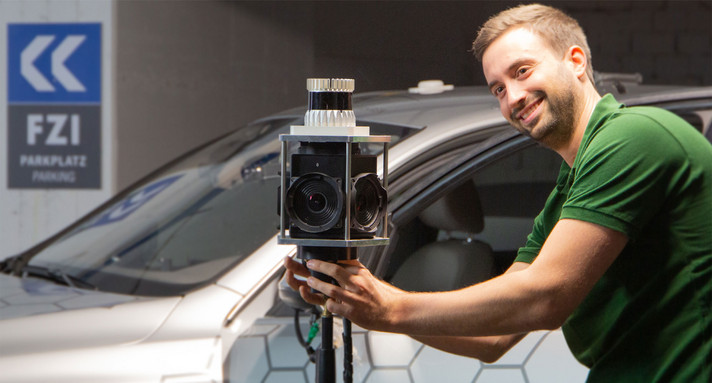 Ein Mann steht vor einem Auto und baut auf einem Stativ einen Sensor auf.