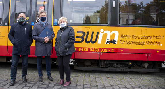 Verkehrsminister Hermann steht gemeinsam mit Oberbürgermeister Mentrup und Wissenschaftsministerin Bauer vor einer Straßenbahn mit der Aufschrift des BW Institut für nachhaltige Mobilität.