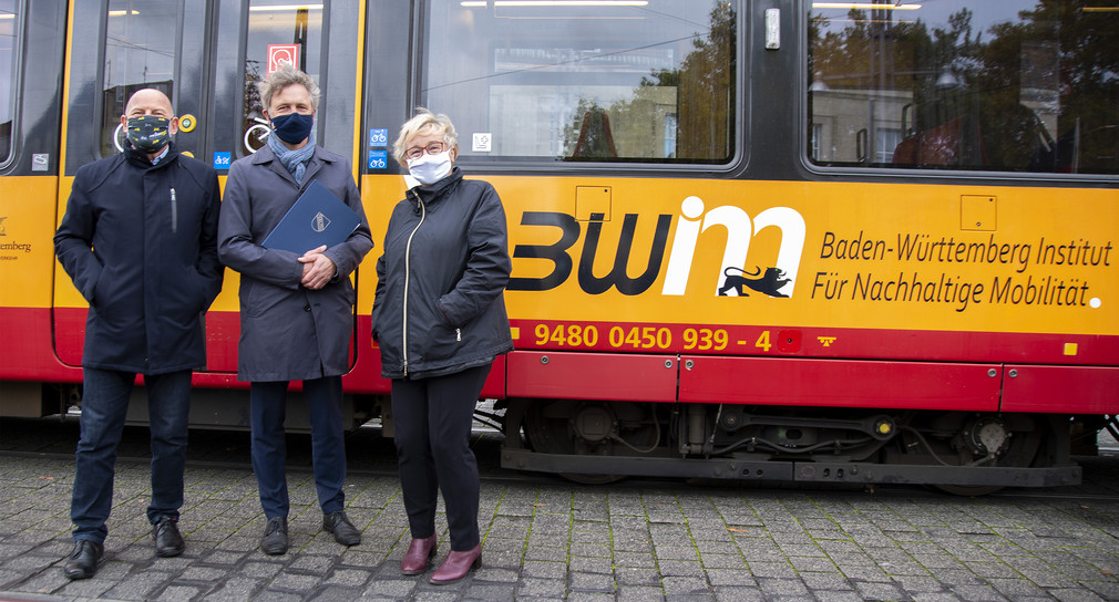 Verkehrsminister Hermann steht gemeinsam mit Oberbürgermeister Mentrup und Wissenschaftsministerin Bauer vor einer Straßenbahn mit der Aufschrift des BW Institut für nachhaltige Mobilität.