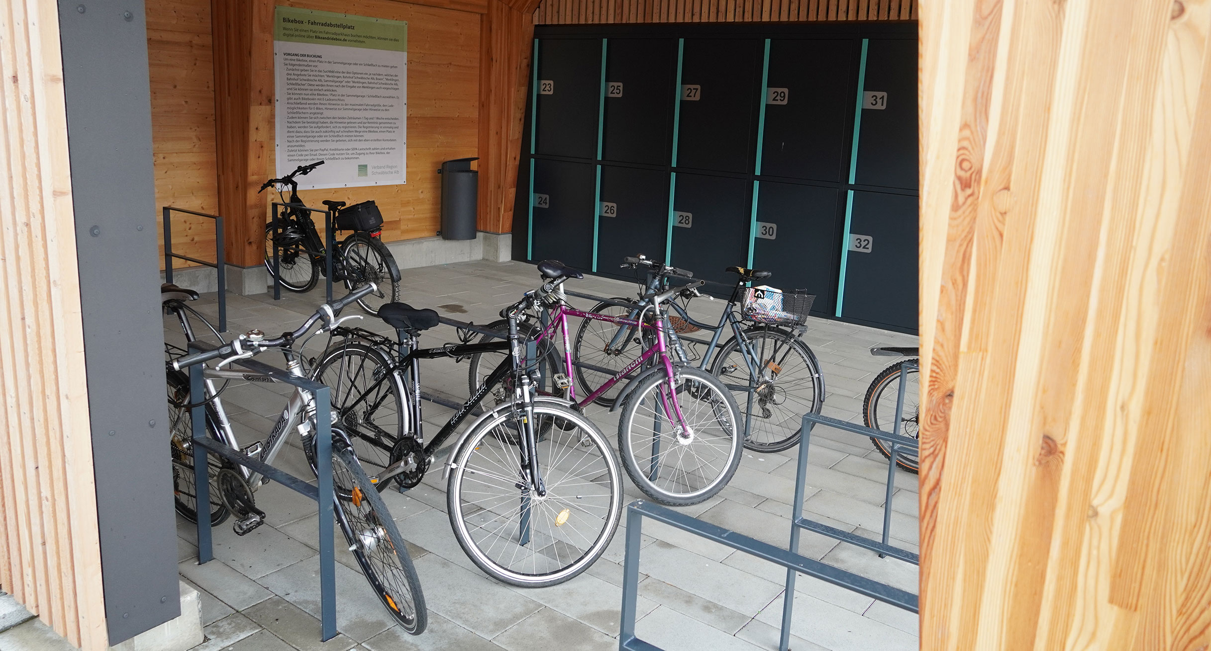 Mehrere Fahrräder stehen unter einem Dach angeschlossen an Fahrradständern.