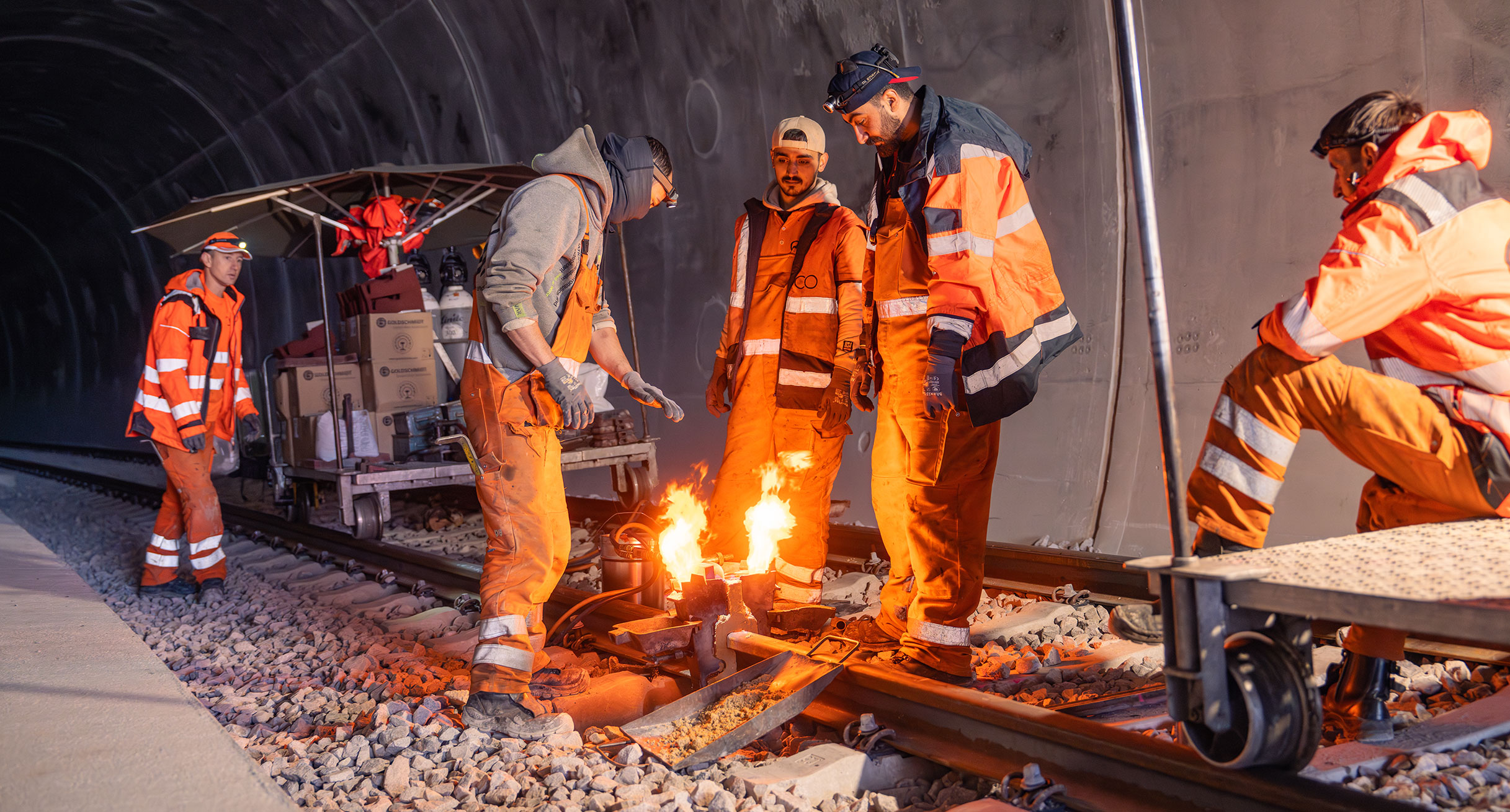 Bauarbeiter schweißen an einer Bahnschiene in einem Tunnel.