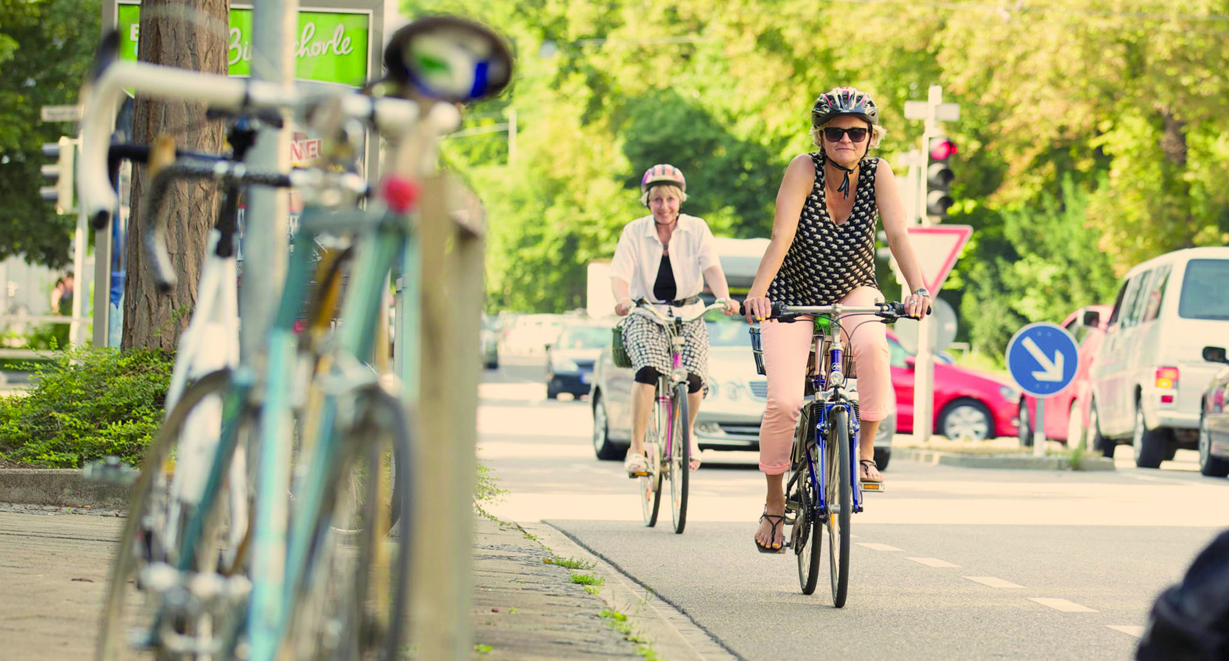 Zwei Radfahrerinnen fahren auf dem Fahrradstreifen einer Straße.