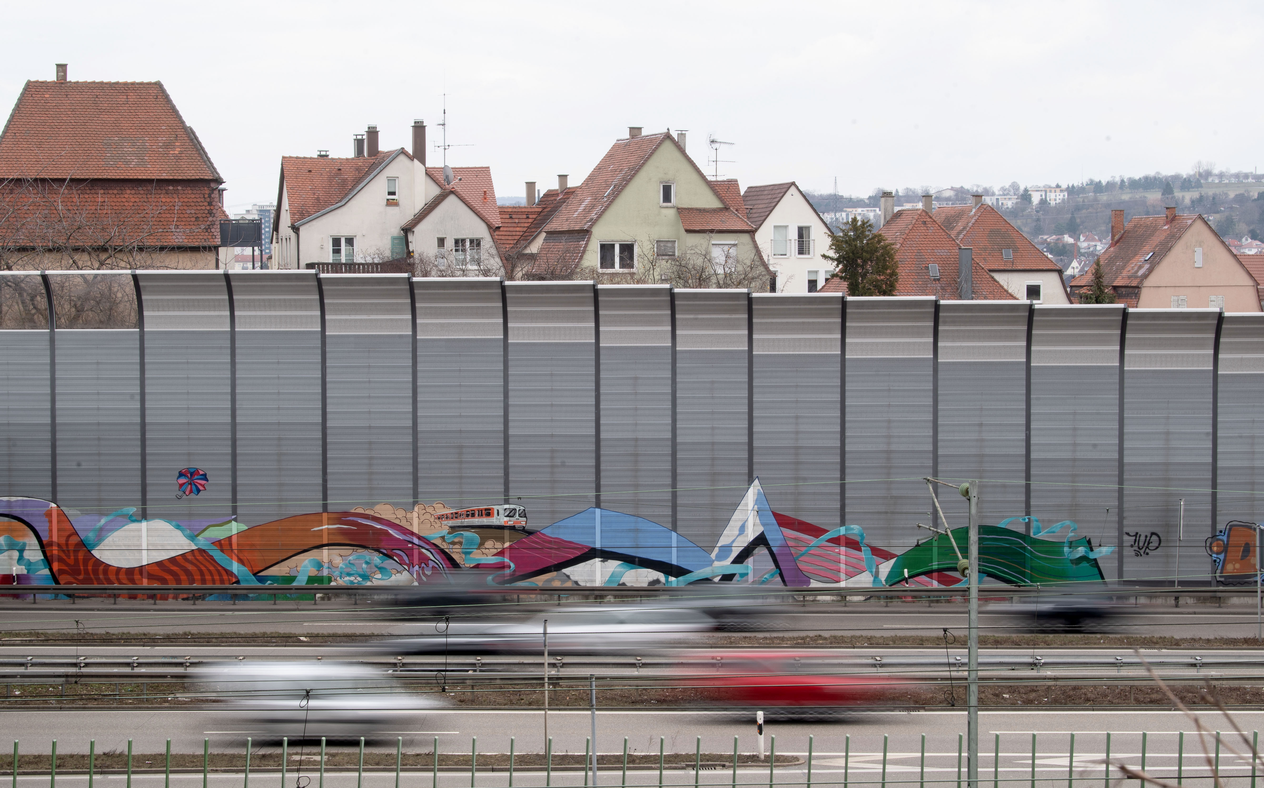 Eine L&auml;rmschutzwand f&uuml;hrt an einer Stra&szlig;e entlang.